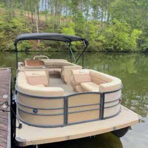 Tan pontoon boat docked at lake.