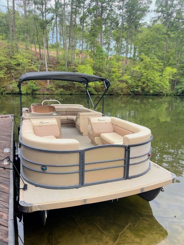 Tan pontoon boat docked at lake.