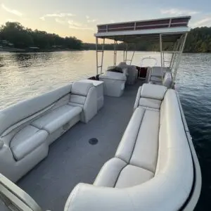 White pontoon boat with seating on lake.