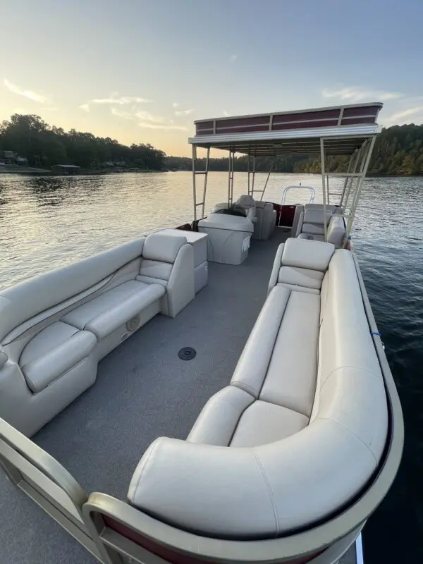 White pontoon boat with seating on lake.