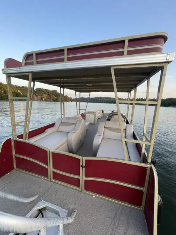 Red and beige pontoon boat on a lake.